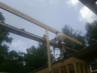 Carpenter setting a ridge beam over a new addition frame — Ice Dam Removal by Roofing Brothers in Annapolis