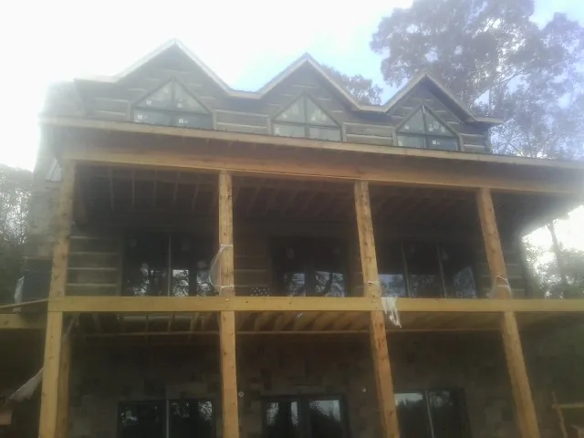 Dormers and porch framing on a large log home under construction — Roof Coating work by our crew in Annapolis