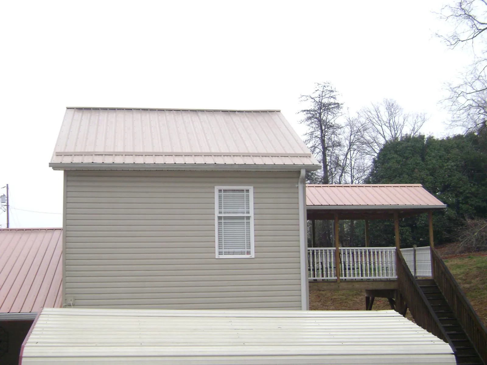Tan metal roofs on a two story addition and attached porch, from a Roof Replacement job in Annapolis
